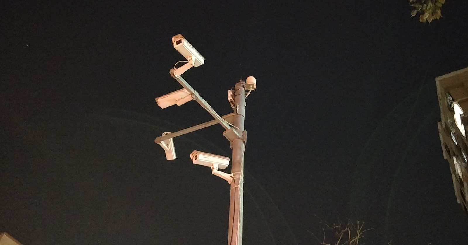 Dwie kamery przemysłowe monitoringu zamontowane na słupie na tle nieba.